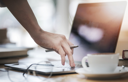 cropped image female hand holding pen and typing on laptop keyboard, working conceptの写真素材