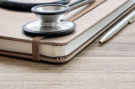 Close up stethoscope and brown diary on wooden tableの写真素材