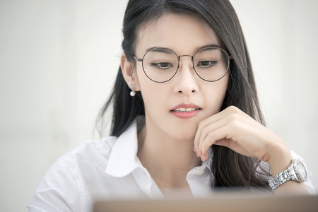 Young businesswoman wearing glasses working with computer in modern office, looking at computer screen.の写真素材