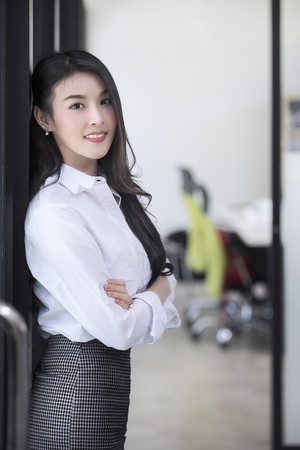 Beautiful businesswoman smiling and standign at the door of her office and looking at cameraの写真素材