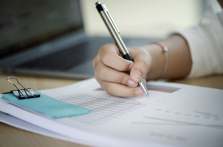 Close up hand of businesswoman writing on paper in officeの写真素材