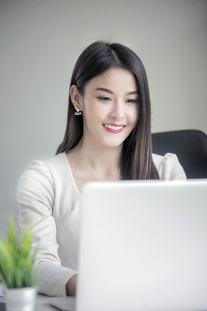 Beautiful brunette using laptop in modern officeの写真素材