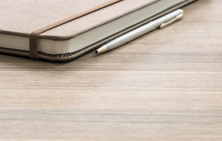 Pen and notebook up close on a  wooden desk with copy spaceの写真素材