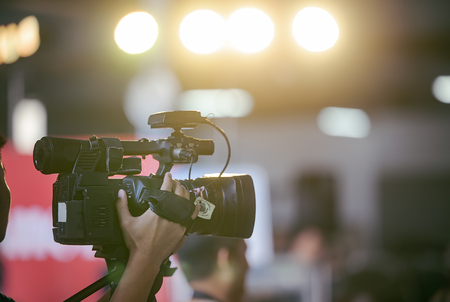 Video camera operator working with his equipment at indoor event.の写真素材