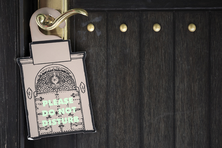 Please do not disturb sign hang on black wooden door of hotel roomの写真素材