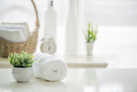 Roll up of white towels on white table with copy space on blurred living room background. For product display montage.の写真素材