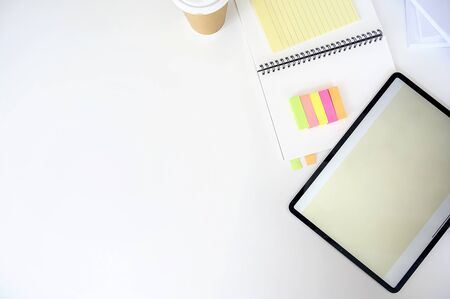 Top view tablet with blank screen, notebook and sticky note on white background, copy space.の写真素材