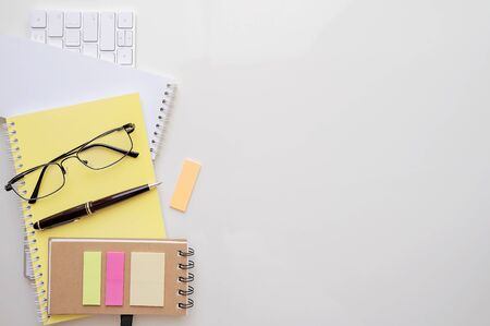 mockup notebook, white keyboard, glasses, pen and sticky note on white background, top view and copy space.の写真素材