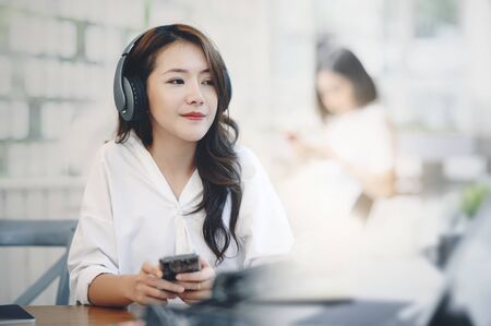 Young woman listening music with headphone while sitting at cafe.の写真素材