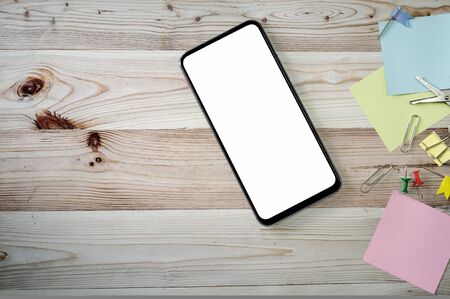 Top view  smartphone with blank screen and supplies on wooden background, copy space.の写真素材