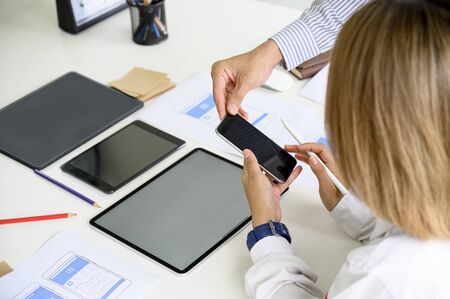 Young creative disigner team working together at office, using smartphone and tablet for new...