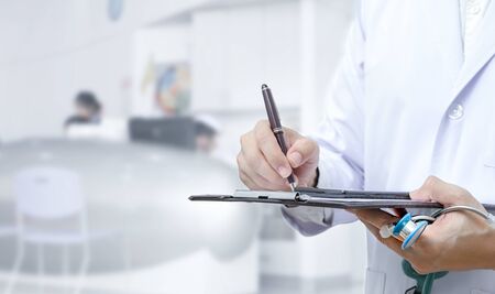 Cropped image of doctor hand writing on application form while standing at hospital. Copy space.の写真素材