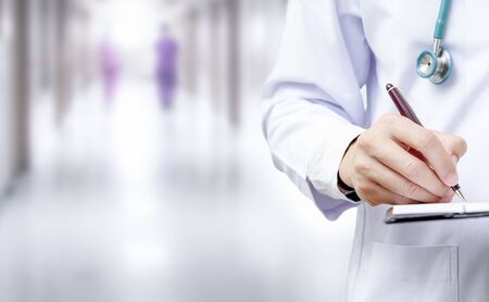 Cropped image of doctor hand writing on application form while standing at hospital. Copy space.の写真素材