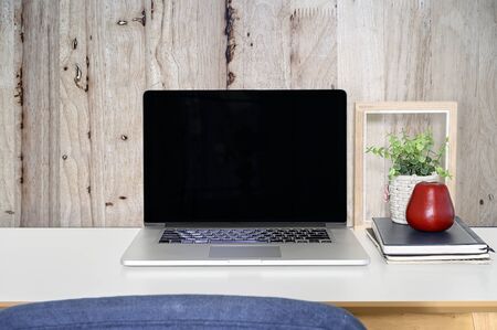 Mockup latop with black screen, books, houseplant and picture frame on white wooden top table, plank wooden wall.の写真素材