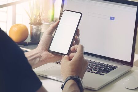 Man sitting at office desk and using the mobile smartphone.