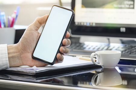 Closeup man using smartphone at  office. Blank screen for graphics display montage.の写真素材
