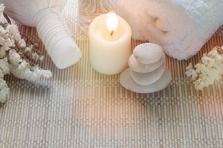 Spa treatments set with herbal compressing ball, oil bottle, candles and towel on bamboo plate background - Beauty and body care conceptの写真素材