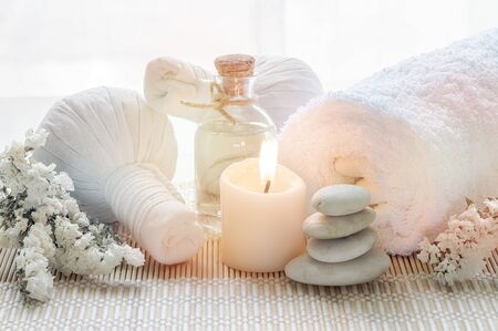 Spa treatments set with herbal compressing ball, oil bottle, candles and towel on bamboo plate background - Beauty and body care conceptの写真素材