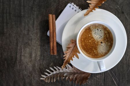 Top view cup of coffee with dry leaf on wooden background, copy space.