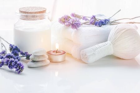 Spa treatments set with herbal compressing ball, oil bottle, candles and towel on wooden background - Beauty and body care conceptの写真素材