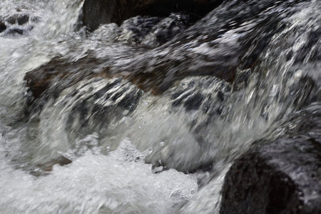 Water flowing over rocks in a stream, closeup of photo.の写真素材