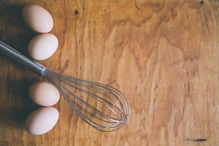 whisk and eggs on wood boardの写真素材