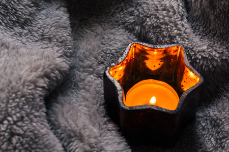 Cosy and soft winter background,candles on a fluffy blanket. Christmas holidays at home.の写真素材