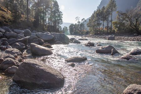 A small creek flowing through the valleys of the himalayan mountains with big rocks and pebblesの写真素材