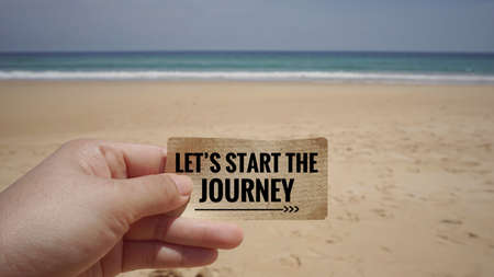 Motivational and inspirational quote - A hand holding a white piece of paper with text âLetâs start the journeyâ on it. Vintage styled background.の写真素材