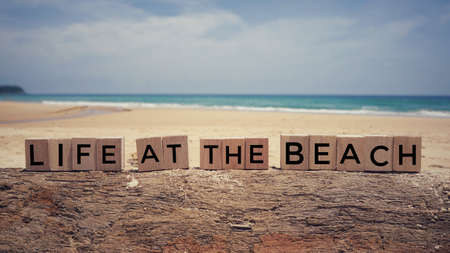Motivational and inspirational quote - âLife at the beachâ written on wooden blocks. Blurred vintage styled background.の写真素材