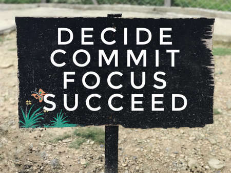 Motivational and inspirational quote - Decide, commit, focus, succeed. On background of black signboard.の写真素材