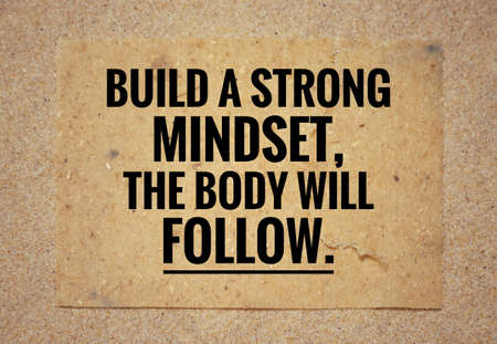 Motivational and inspirational quote - Build a strong mindset, the body will follow. With background of beach sand.の写真素材