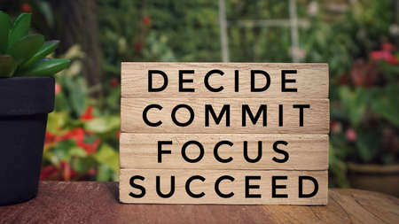 Motivational and inspirational quote - âDECIDE, COMMIT, FOCUS, SUCCEEDâ written on wooden blocks. Vintage styled background.の写真素材