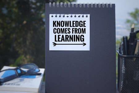 Educational and motivational  quote - âKnowledge comes from learningâ written on a white paper. Blurred styled background.の写真素材