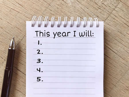 New year resolutions concept - New Year Resolutions List on a Notepad on wooden table.の写真素材