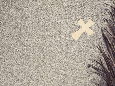 Ash Wednesday concept - A religious cross formed out of ashes. Thereâs a dry palm leaf beside it.の写真素材