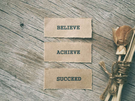 Motivational and inspirational words - Believe, Achieve, Succeed written on papers and arranged on a...
