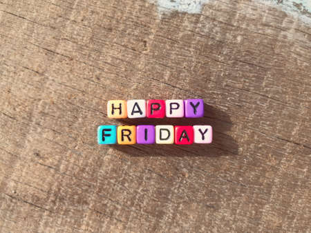 Happy Friday written on colored blocks and arranged on a wooden table.