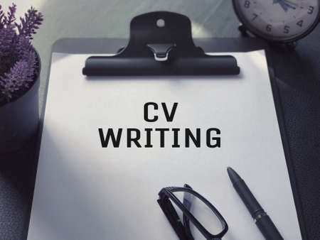 Business or Job Hiring concept - Top view of a clipboard and white sheet with CV WRITING written on it.の写真素材