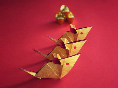 Chinese New Year concept. Golden origami rats and golden ingots on red background.
