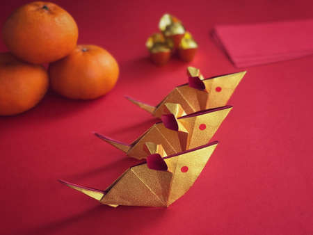 Chinese New Year concept. Golden origami rats, golden ingots, mandarin oranges and ang paos on red background.の写真素材