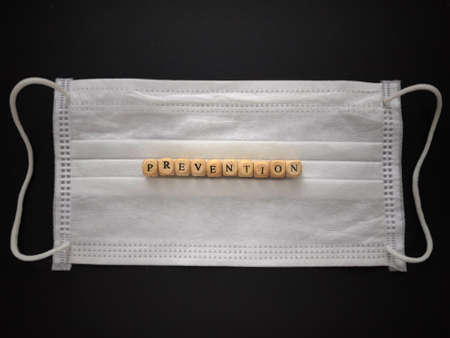 Health care and medical concept. PREVENTION written on wooden blocks on background of medical face mask.の写真素材