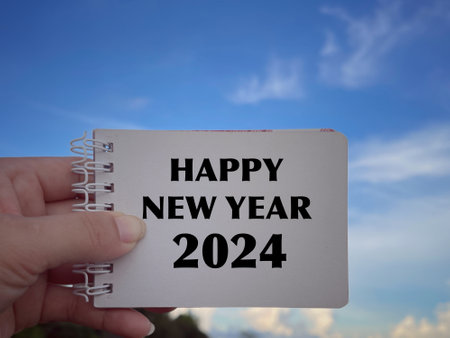 New Year Celebration Concept. Happy New Year 2024 written on a notepad. With blurred styled background.の写真素材