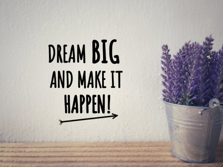 Motivational and inspirational wording. DREAM BIG AND MAKE IT HAPPEN written on a white wall. With blurred vintage styled background.の写真素材
