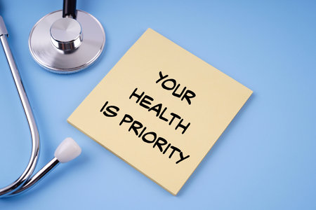Motivational health and medical concept.YOUR HEALTH IS PRIORITY written on a paper. On blue background.の写真素材
