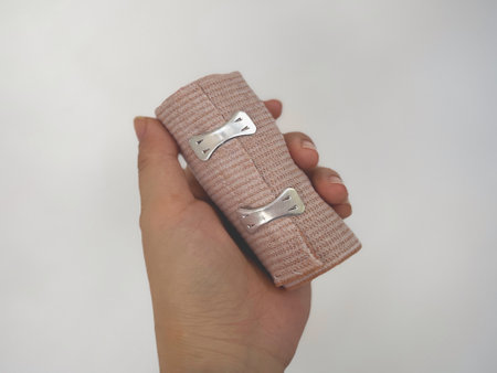 Medical care and health concept. Hand holding a piece of cohesive bandage on white background.の写真素材