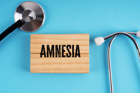 AMNESIA text on wooden block with stethoscope on blue background