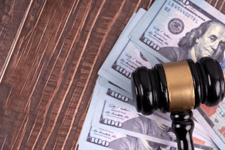 Wooden judge gavel and dollar banknotes on wooden background.