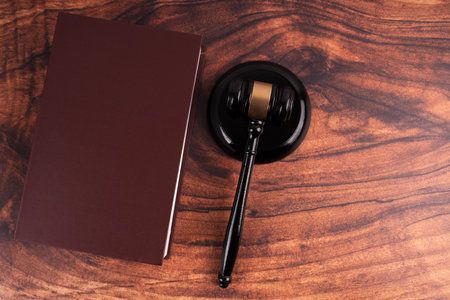Wooden judge gavel and book on wooden table. Top view