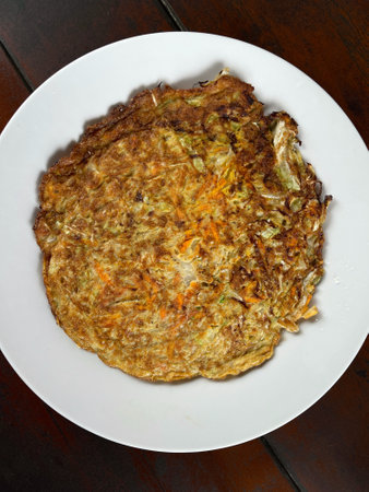 Omelet with carrot and onion on white plate, top viewの写真素材